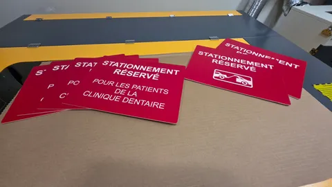 Laser engraved red parking signs for a dental clinic inside a fabrication shop.