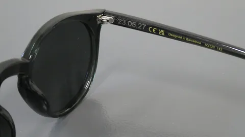 Close-up of a custom date "23.05.27" laser engraved on the inner temple of black sunglasses.